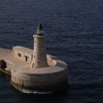 Malta’nın tarihi sokaklarında gezen insanlar ve deniz manzarası